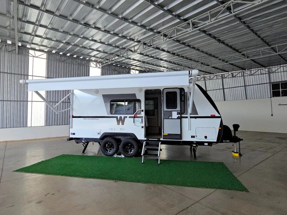Winnebago 2108DS em vista lateral externa, com toldo aberto, porta, rodas e engate visíveis